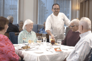 John Knox Village Executive Chef Frederic Delaire visits a table to check in with residents about their meal
