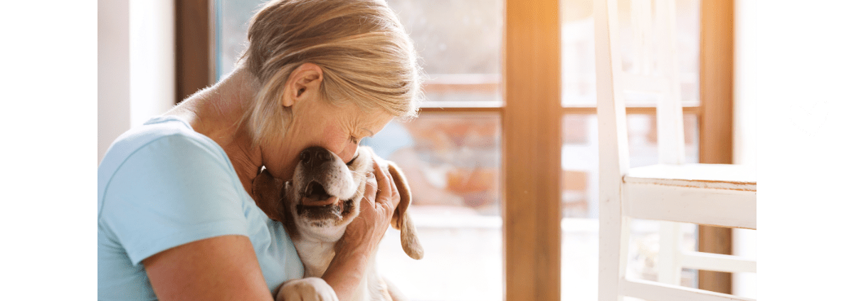 older woman hugging and kissing a beagle